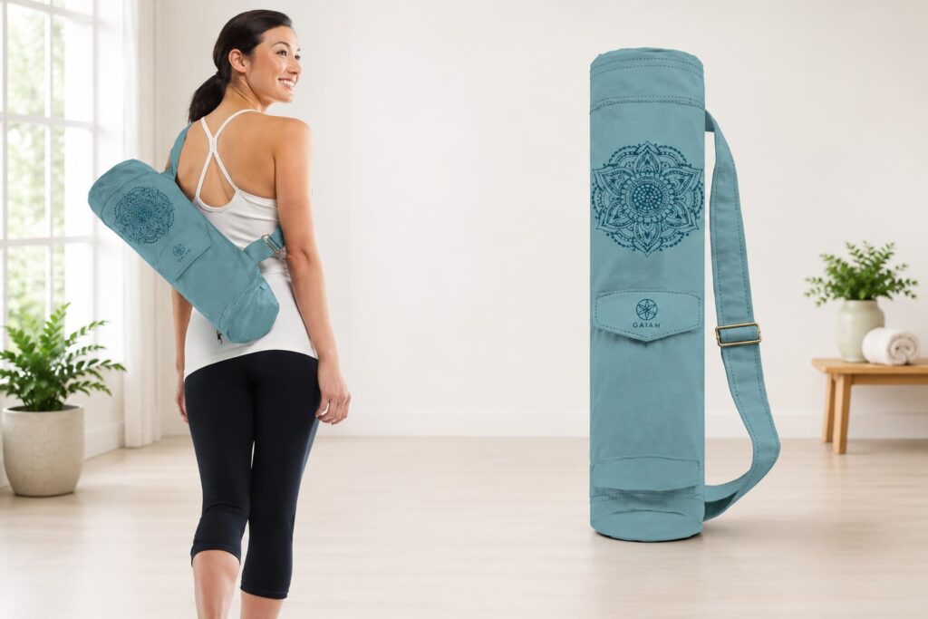 Woman carrying a Gaiam Cargo Yoga Mat Bag with adjustable strap in a bright yoga studio.