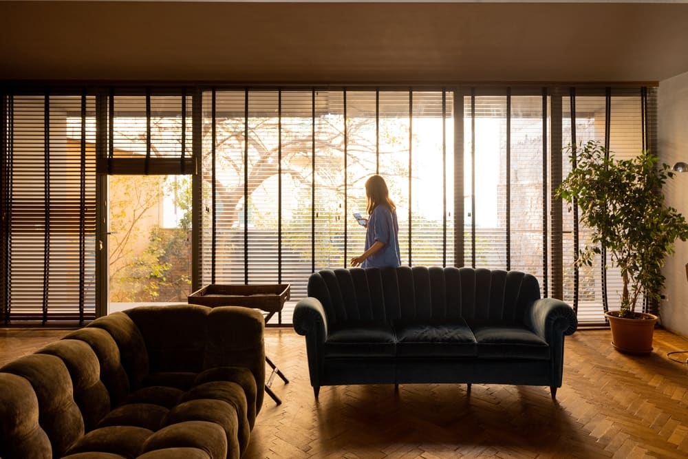 Woman walking indoors near large windows in a modern living room to stay active at home.